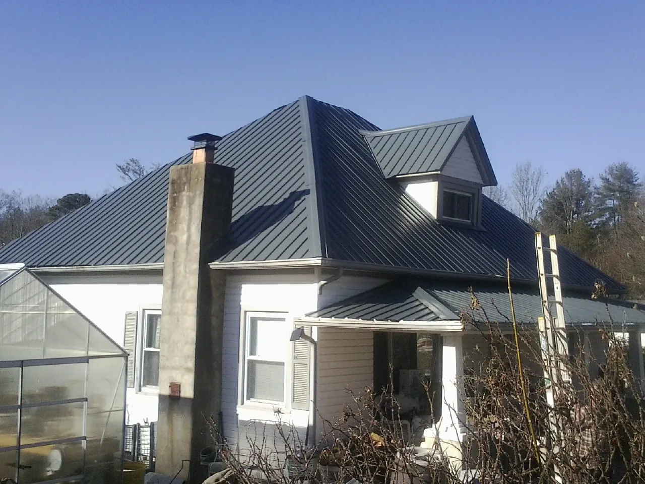 Dark blue standing seam metal roof on a white farmhouse with dormer — Slate & Tile Roof Repair by Roofing Brothers in Lagrangeville