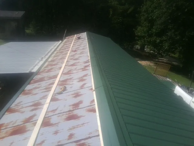 Old rusted panels beside newly installed green metal roofing — Wind Damage Roof Repair by Roofing Brothers in Lagrangeville