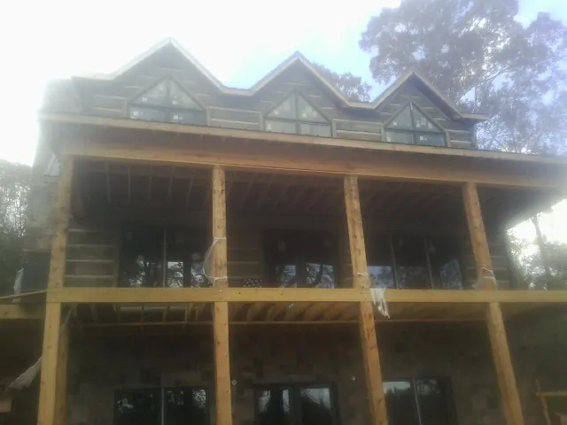 Dormers and porch framing on a large log home under construction — Roof Coating work by our crew in Lagrangeville