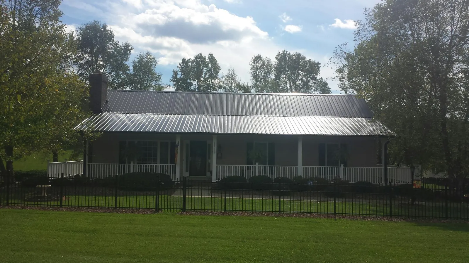 Gray metal roof on a brick ranch with a full width front porch — Gutter Guard Installation work by our crew in Lagrangeville