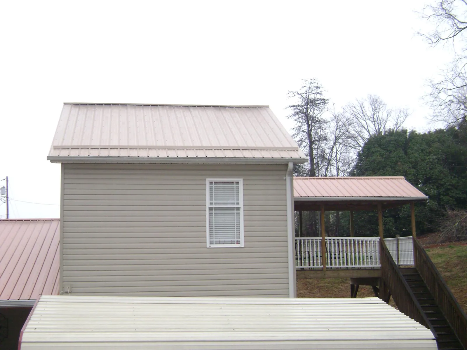 Tan metal roofs on a two story addition and attached porch, from a Roof Replacement job in Lagrangeville