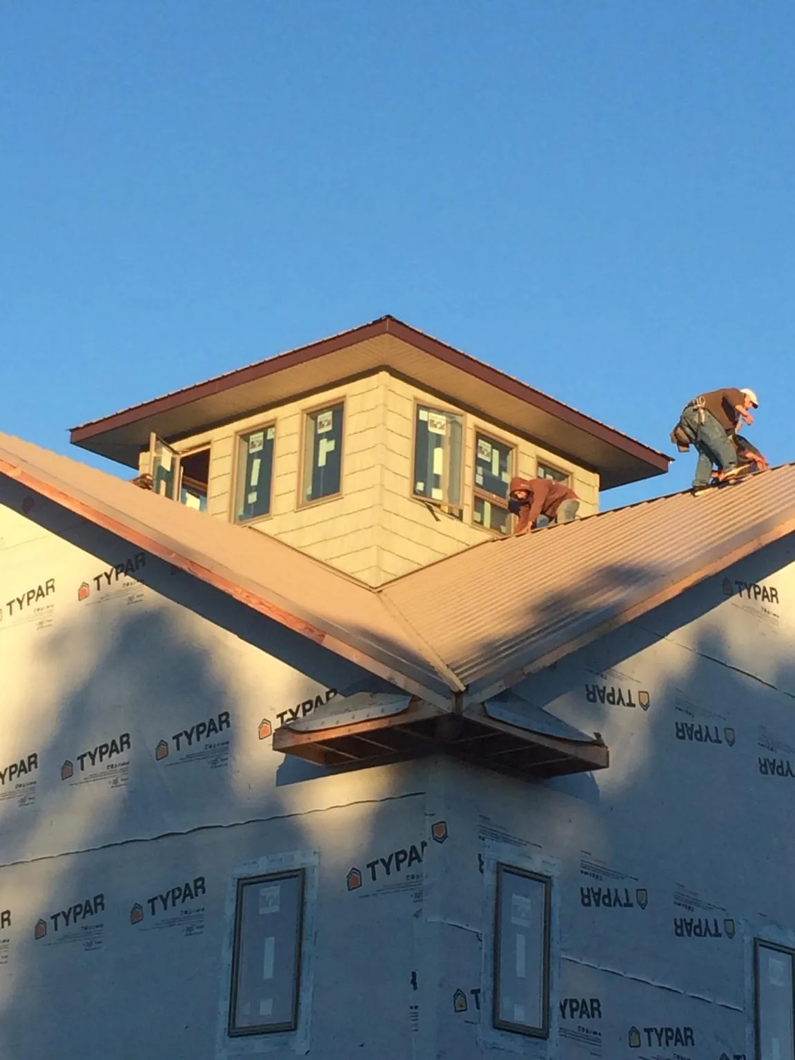 Roofers working around a rooftop cupola on a new metal roof at sunset — Roof Waterproofing in Lagrangeville by Roofing Brothers